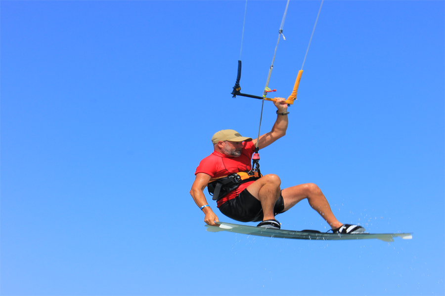 Man kitesurfing in the air above the sea, showing balance, power, and freedom