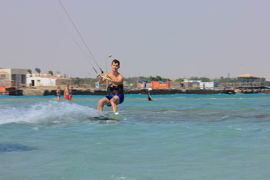Man kitesurfing on the sea, gliding smoothly across the waves under a clear blue sky