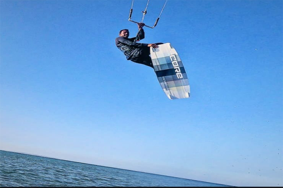 Man kitesurfing in the air above the sea, showing balance, power, and freedom