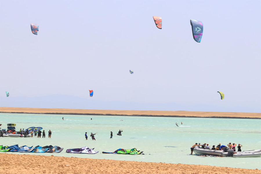 Group of kitesurfers riding the waves in deep water with a yacht in the background at Hurghada