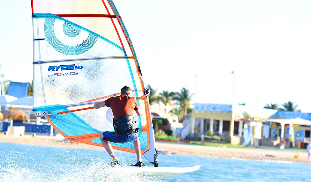 Beginner windsurfer standing in shallow water Hurghada Egypt safe lagoon learning."