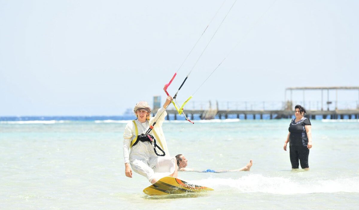 Estudiante volando una cometa de entrenamiento en una playa de arena
