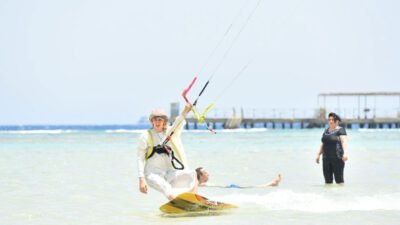 Estudiante volando una cometa de entrenamiento en una playa de arena