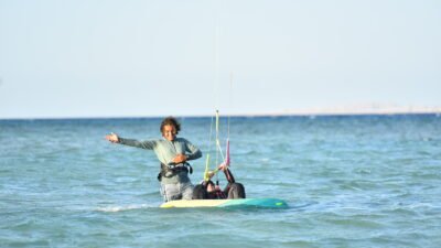 Masters Surf School instructor teaching a child kitesurfing in shallow Hurghada lagoon