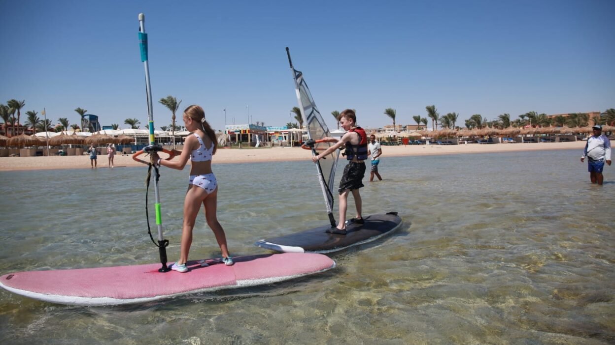 Family windsurfing in Hurghada's shallow lagoon with children learning on small boards
